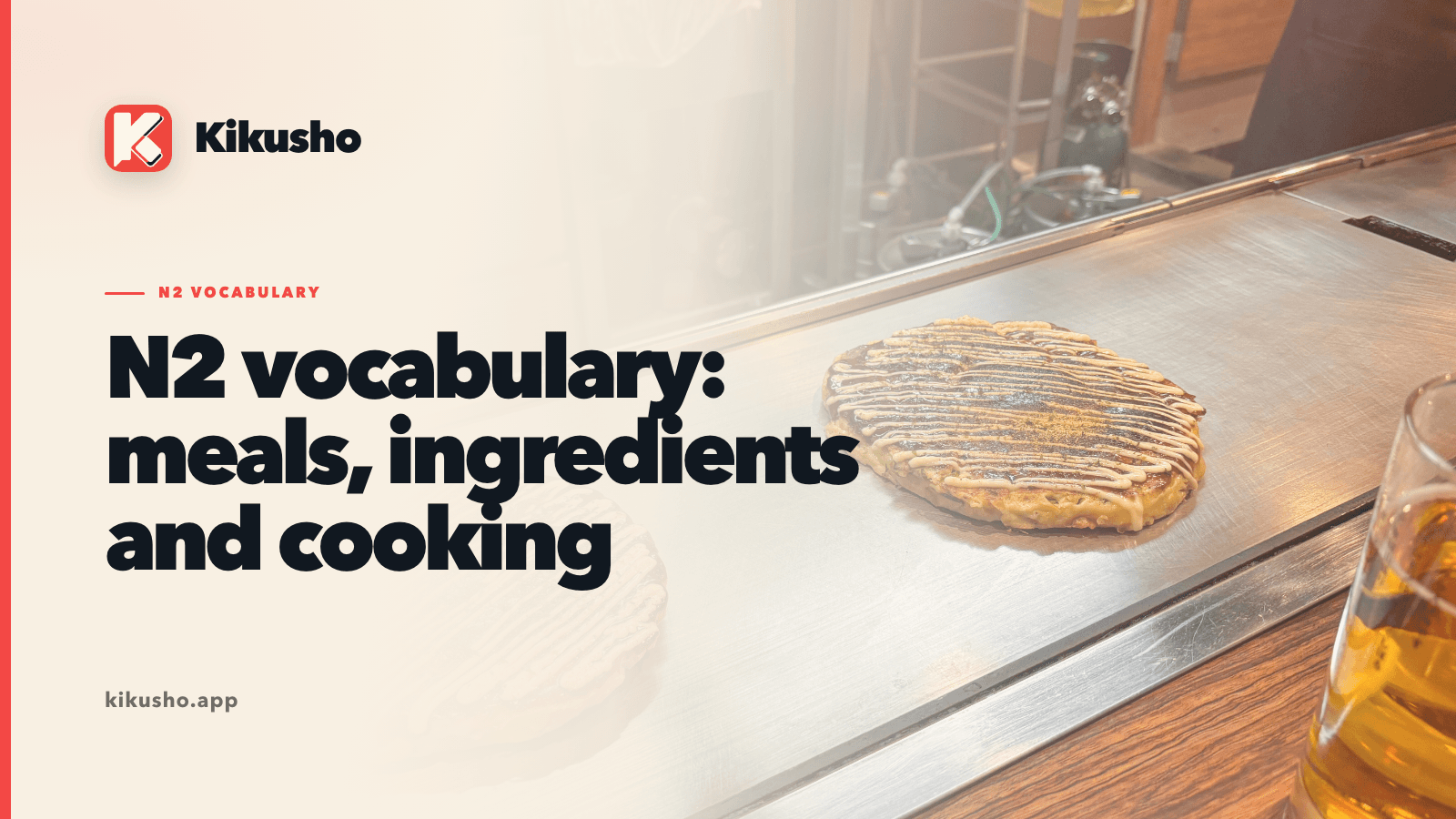 Kikusho N2 vocabulary title card over an okonomiyaki cooking on a restaurant griddle, with sauce and seasoning on top.